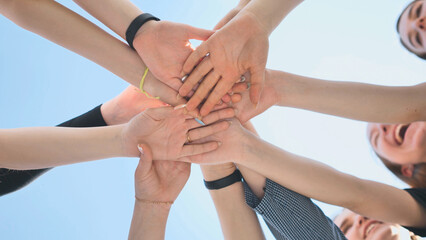 Cheerful girls join hands together as a sign of unity and joint successful work. Teamwork stacking hand concept.