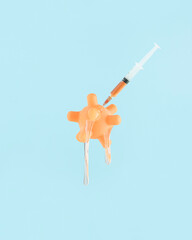 Model of coronavirus with slime, syringe and needle, melts and decomposes on isolated pastel blue background. After vaccination abstract surreal creative concept. Minimal card. End Covid-19 pandemic.