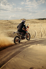 Obraz na płótnie Canvas Professional motocross rider driving on sand dune