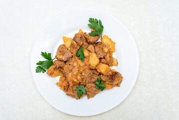 Top view of roast pork, parsley potatoes in a white plate.