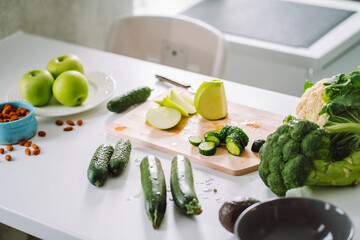White dinner table with vegetable. Green apples, cucumber, avocado, almonds, zucchini cabbage on...