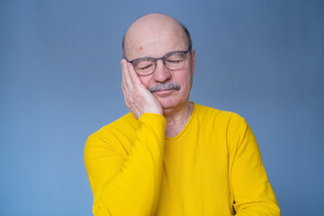 Senior man in glasses sleeping tired dreaming smiling with closed eyes.