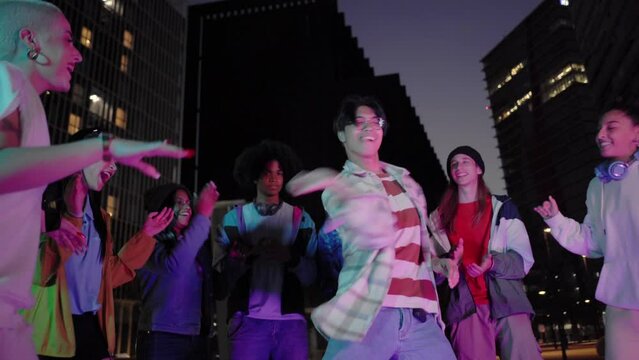 Multiracial Group of freestyle dancers performing different moves on the dark street.