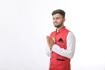 Young indian man in traditional wear and giving namaste or welcome gesture.