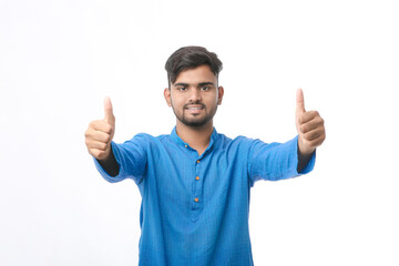young indian man in traditional wear and showing thumps up on white background.
