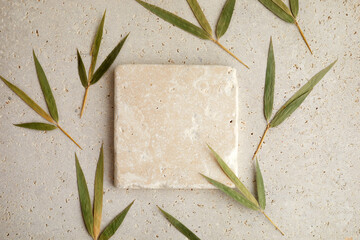Travertine stone display flat lay podium on biege background and bamboo leaves. Product promotion...