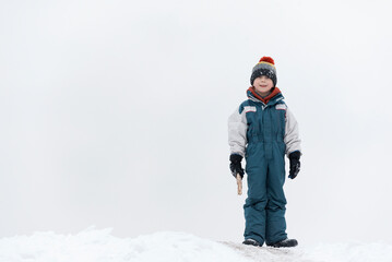 Fototapeta na wymiar Boy plays outside during snowfall. Winter holidays. Child walks outdoors in winter.