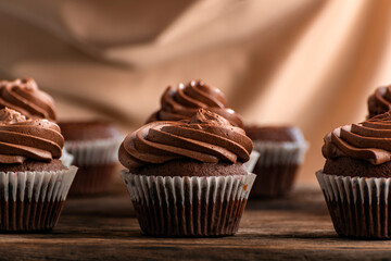 Chocolate cupcakes with butter cream tops on wooden table. Delicious chocolate muffins close up.