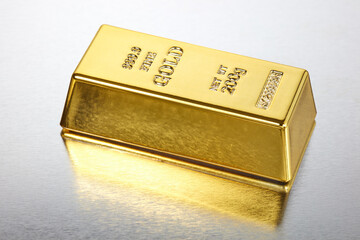 Ein Goldbarren liegt auf einem spiegelnden Untergrund.