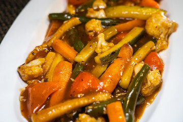 Close up of sautéd exotic vegetables - Zucchini, Baby corn, Broccoli, Beans, Carrots, Mushrooms, Cauliflower and Bell Peppers mixed in black pepper sauce. 