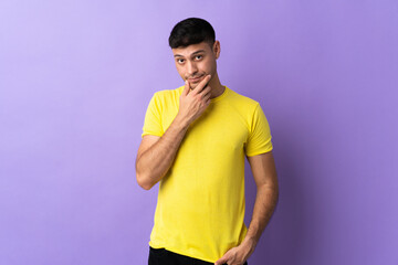 Young Colombian man isolated on purple background thinking