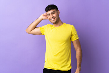 Young Colombian man isolated on purple background laughing