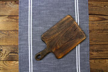 Closeup cutting board tablecloth. wooden background. Linen table cloth on brown wood textured tabletop. Mock up, copy space. Kitchen workspace flat lay, top view. Cooking workplace. Thanksgiving day
