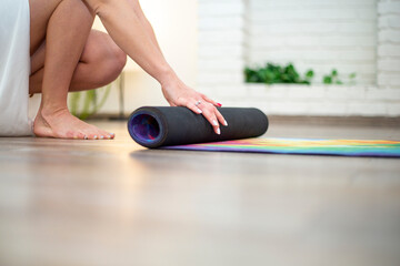 Close-up of a woman's hands rolling up an exercise mat and getting ready for a yoga class. With copyspace for text or logo