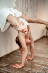 Portrait of a young woman practicing yoga indoors in studio. Beautiful girl Warm-up before difficult exercises.  female menthal health. 6Soft focus on female's foot