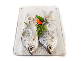 Gerres Fish (Gerres Filamentosus) Whipfin silver biddy Fish, Decorated with vegetables on a glass bowl, White Background.Selective Focus