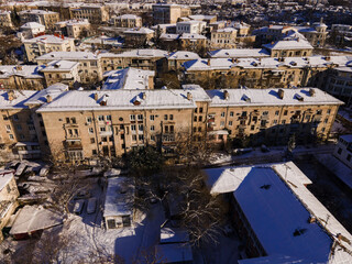 Snow-covered streets of the city from the air. The roads are covered with snow. Roofs of houses in the snow. Snow covered yards. Winter fairy tale in the city from the air.