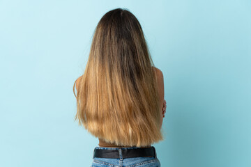 Young caucasian woman isolated on blue background in back position