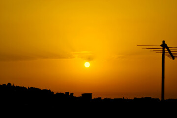 Orange yellow sunset with the silhouette of an antenna on the right side.
sunset over the city