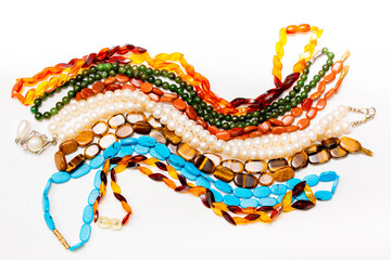 Beads and necklaces made of colored semi precious stones. Background from a variety of beautiful jewelry, multi-colored turquoise stones, amber, cat's eye, pearls.