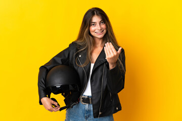 Woman holding a motorcycle helmet isolated on yellow background inviting to come with hand. Happy that you came