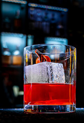 Cocktail Negroni with gin, campari martini rosso and orange in glass on bar counter
