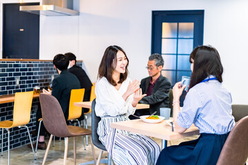 明るい雰囲気の社員食堂でランチを取るオフィスワーカー