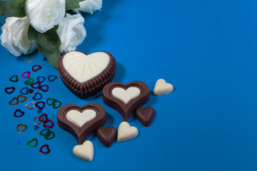 chocolate bonbons with heart shapes and white roses