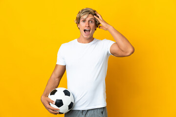 English football player over isolated yellow background with surprise expression