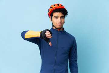 Venezuelan cyclist man isolated on blue background showing thumb down with negative expression