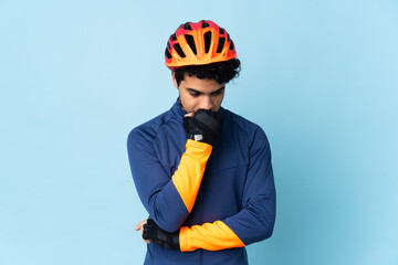 Venezuelan cyclist man isolated on blue background having doubts - obrazy, fototapety, plakaty