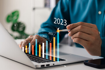 Businessman analyzes profitability of working companies with digital augmented reality graphics, positive indicators in 2023, businessman calculates financial data for long-term investments. - obrazy, fototapety, plakaty