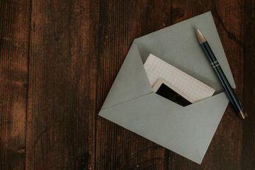 Paper envelope with a letter and photos of the inside on a wooden background.