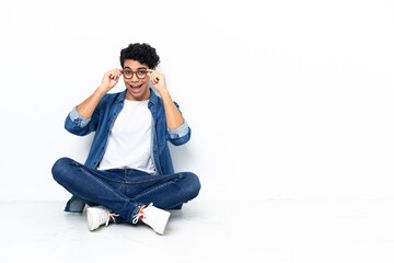 Venezuelan man sitting on the floor with glasses and surprised