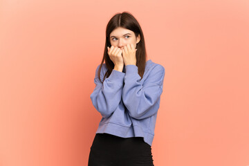 Young Ukrainian girl isolated on pink background nervous and scared putting hands to mouth