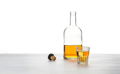 A glass and a bottle of alcohol with a cork on a white background.