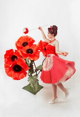 Beautiful female portrait with large flowers of red poppies in pin-up style. housewife girl removes dust from growing flowers