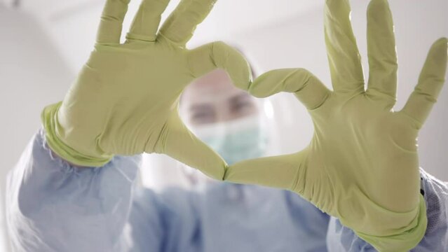 Equipped surgeon shows a heart with his hands and smille. High quality 4k footage.concept dentist