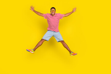 Fototapeta na wymiar Full length photo of youth guy jump hold hands aside wear red striped outfit isolated over bright yellow color background