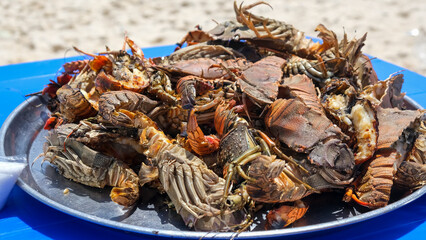 Large plate with a grilled seafood lobsters. BBQ exotic food on the beach. Selective focus.
