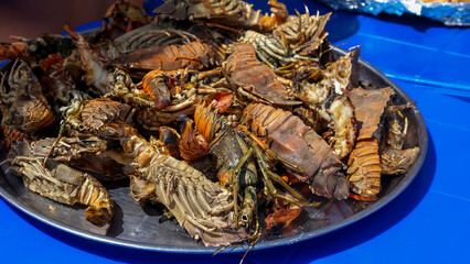 Large plate with a grilled seafood lobsters. BBQ exotic food on the beach. Selective focus.