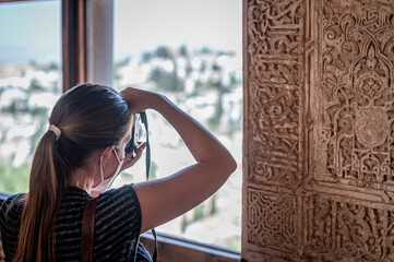 Young girl taking photos inside the alhambra - obrazy, fototapety, plakaty