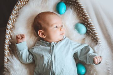 Cute baby Easter bunny. Little baby boy with bunny ears and Easter eggs in wicker basket in white...