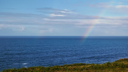 rainbow disappearing into the wild blue ocean