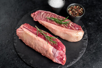 Two raw picanha steaks with spices on a stone background