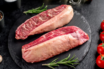 Two raw picanha steaks with spices on a stone background