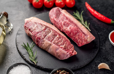 Two raw picanha steaks with spices on a stone background