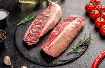 Two raw picanha steaks with spices on a stone background