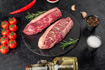 Two raw picanha steaks with spices on a stone background