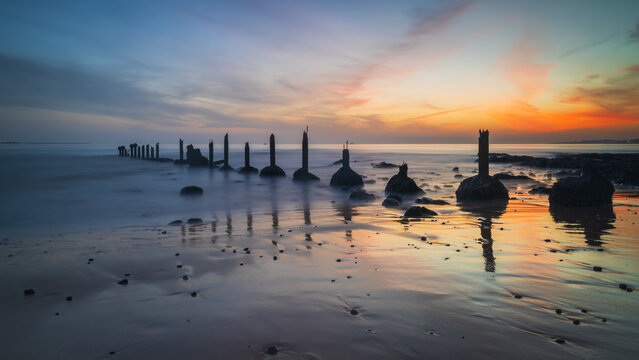 Long exposure image with old pillar stucture by Tagus river in Portugal at sunset